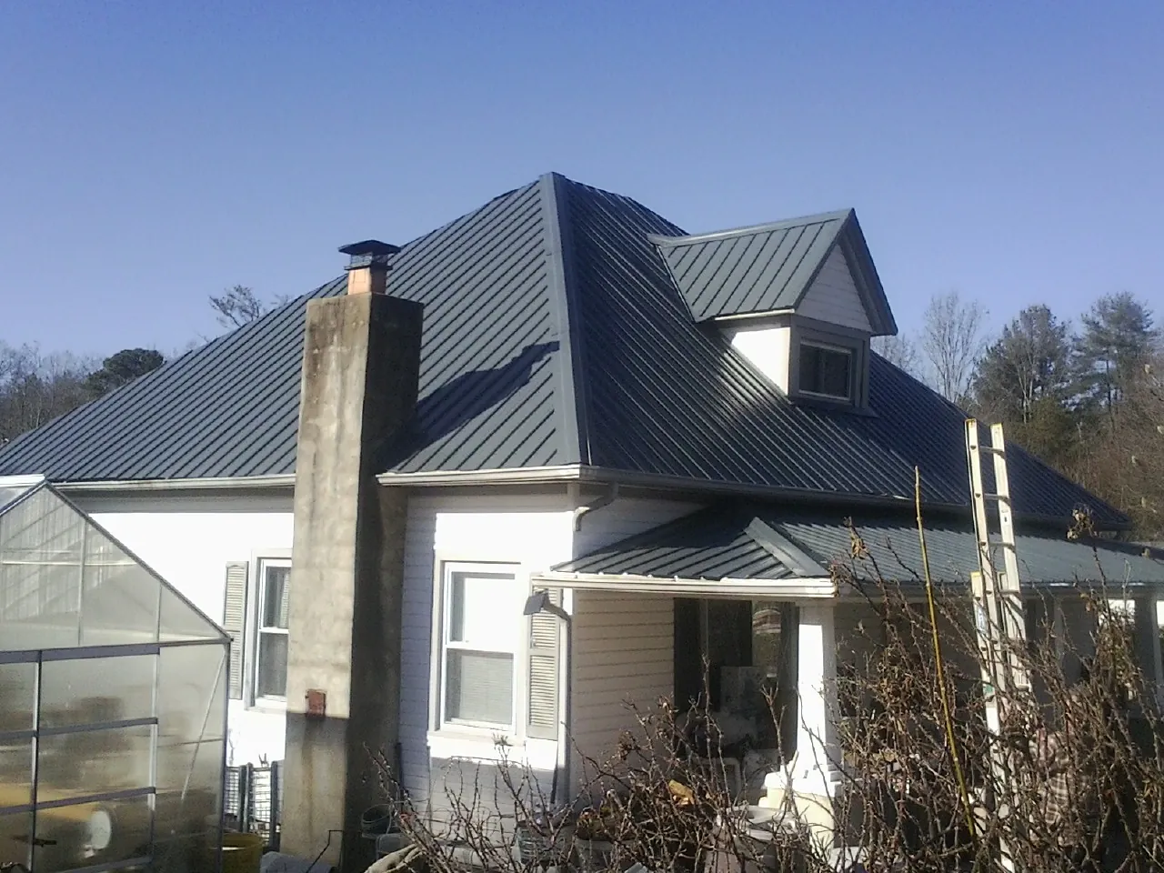 Dark blue standing seam metal roof on a white farmhouse with dormer — Slate & Tile Roof Repair by Roofing Brothers in Point Reyes Station