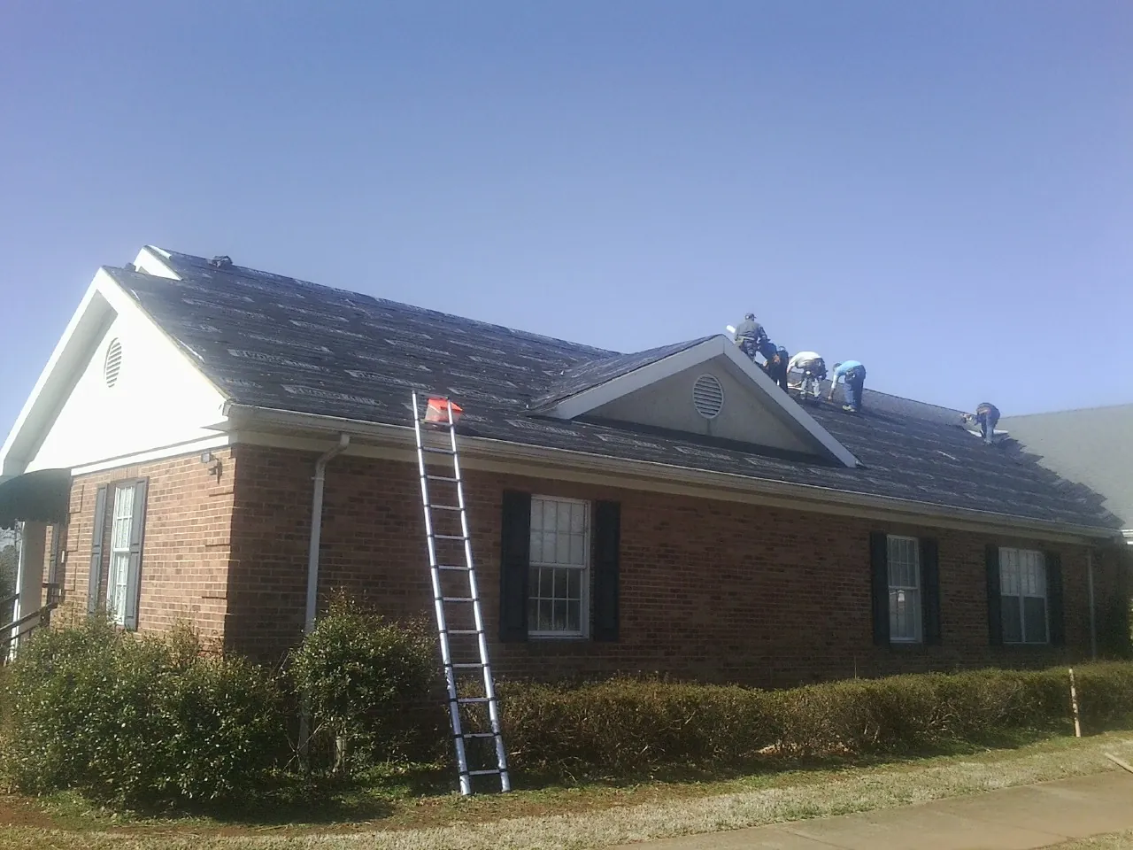 Crew tearing shingles off a brick ranch roof with a ladder set — Metal Roof Repair work by our crew in Point Reyes Station
