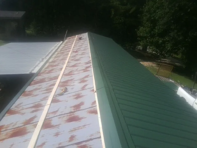 Old rusted panels beside newly installed green metal roofing — Wind Damage Roof Repair by Roofing Brothers in Point Reyes Station