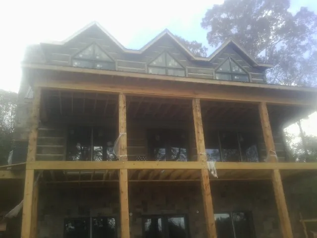 Dormers and porch framing on a large log home under construction — Roof Coating work by our crew in Point Reyes Station
