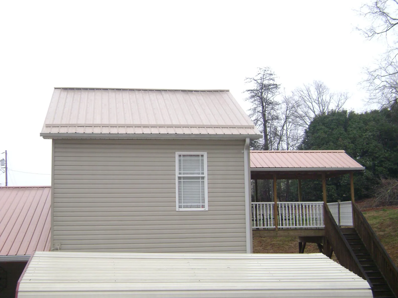 Tan metal roofs on a two story addition and attached porch, from a Roof Replacement job in Point Reyes Station