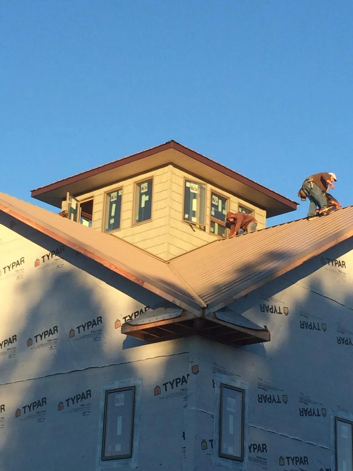 Roofers working around a rooftop cupola on a new metal roof at sunset — Roof Waterproofing in Point Reyes Station by Roofing Brothers